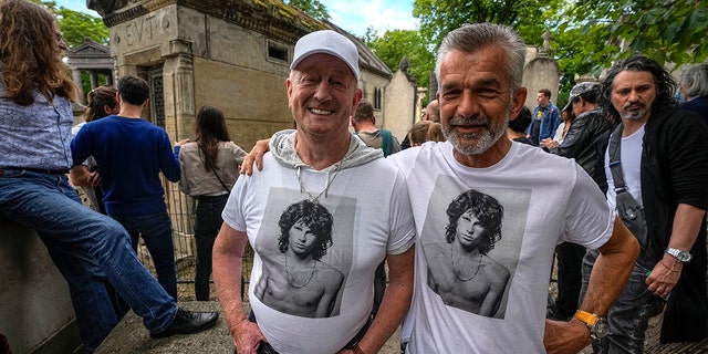 Fred Verheijden, left, and Hans van Schie from the Netherlands wear shirts with a photo of the late rock singer Jim Morrison in the Pere-Lachaise Cemetery in Paris, Saturday 3 July 2021. (Associated Press)