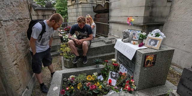 Joachim Tittmar of Germany, left, Walter Homburg of the Netherlands, in the middle, and his girlfriend Kate Schirm arrive at the grave of rock singer Jim Morrison at the Pere-Lachaise Cemetery in Paris, Saturday, July 3, 2021. (Associated Press )