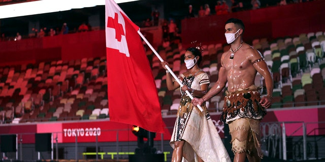 Malia Paseka and Pita Taufatofua of Tonga carry their country's flag during the opening ceremony at the Olympic Stadium for the 2020 Summer Olympics on Friday, July 23, 2021, in Tokyo, Japan.  (Hannah McKay / Pool Photo via AP)