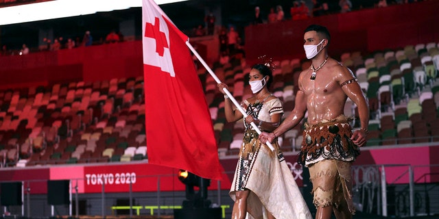 Malia Paseka and Pita Taufatofua, of Tonga, carry their country's flag during the opening ceremony in the Olympic Stadium at the 2020 Summer Olympics, Friday, July 23, 2021, in Tokyo, Japan. (Hannah McKay/Pool Photo via AP)