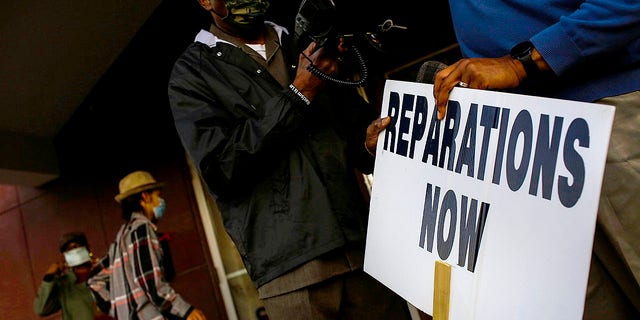 Vernon AME Church Pastor Robert Turner holds a reparations now sign after leading a protest from City Hall back to his church in the Greenwood neighborhood on Nov. 18, 2020 in Tulsa, Oklahoma.