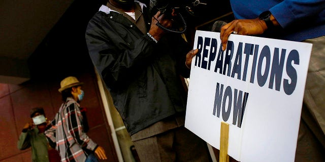 Vernon AME Church Pastor Robert Turner holds a reparations now sign after leading a protest from City Hall back to his church in the Greenwood neighborhood on Nov. 18, 2020 in Tulsa, Oklahoma.