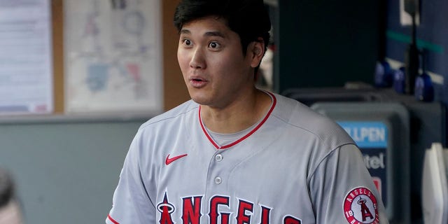 Los Angeles Angels' Shohei Ohtani reacts in the dugout after he scored on a sacrifice fly hit by Phil Gosselin during the ninth inning of a baseball game, Sunday, July 11, 2021, in Seattle. (AP Photo/Ted S. Warren)