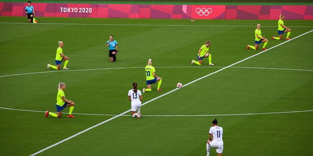 The players kneel before the opening match of the women's soccer first round between the United States and Sweden at the Tokyo 2020 Olympic Games in Tokyo, Japan on Wednesday, July 21, 2021. The games will be the first in modern history to unfold without spectators, after Tokyo entered another state of emergency that will last throughout the tournament.  Photographer: Noriko Hayashi / Bloomberg via Getty Images