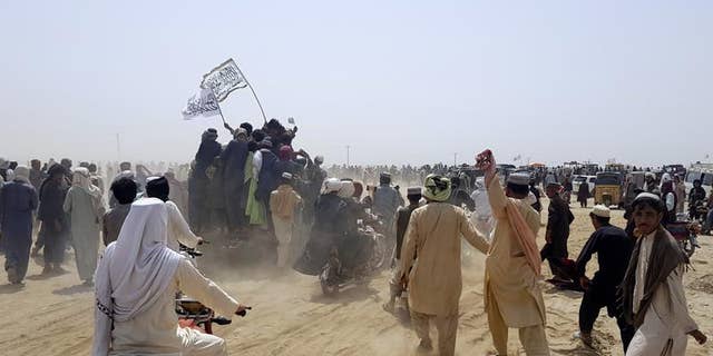 Supporters of the Taliban carry the Taliban's signature white flags in the Afghan-Pakistan border town of Chaman, Pakistan, Wednesday, July 14, 2021. (AP Photo/Tariq Achkzai)