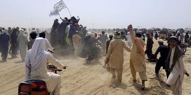 Supporters of the Taliban carry the Taliban's signature white flags in the Afghan-Pakistan border town of Chaman, Pakistan, Wednesday, July 14, 2021. The Taliban are pressing on with their surge in Afghanistan, saying Wednesday that they seized Spin Boldaka, a strategic border crossing with Pakistan, the latest in a series of key border post to come under their control in recent weeks. (AP Photo/Tariq Achkzai)