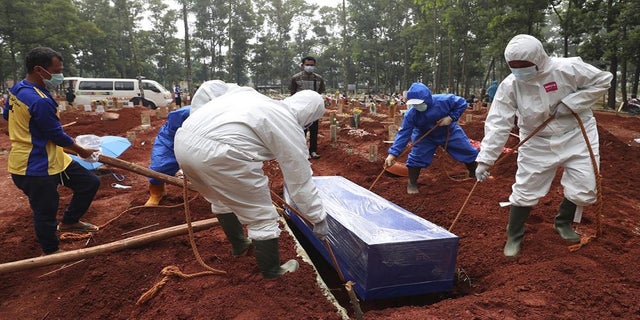 July 14, 2021: Workers in protective gear lower a coffin of a COVID-19 victim to a grave for burial at the Cipenjo Cemetery in Bogor, West Java, Indonesia. The world's fourth most populous country has been hit hard by an explosion of COVID-19 cases that have strained hospitals on the main island of Java. 