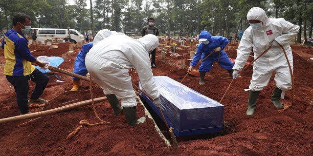 July 14, 2021: Workers in protective gear lower a coffin of a COVID-19 victim to a grave for burial at the Cipenjo Cemetery in Bogor, West Java, Indonesia. The world's fourth most populous country has been hit hard by an explosion of COVID-19 cases that have strained hospitals on the main island of Java. 