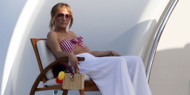 Jennifer ha preso il sole indossando il suo bikini top a righe succinti mostrando la sua pancia tonica e sdraiata sul loro $  130M yacht.