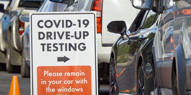 A "COVID-19 Drive-Up Testing" sign is seen at a drive-thru testing site.