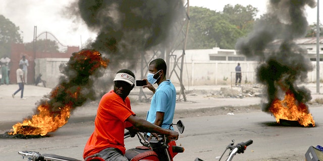 Supporters of former senator Youri Latortue and Steven Benoit set tires on fire outside the Port-au-Prince courthouse on Monday, July 12, 2021. Prosecutors have called for prominent politicians like Latortue and Benoit meet with officials for questioning in connection with the investigation into the assassination of President Jovenel Moise.  (AP Photo / Joseph Odelyn)