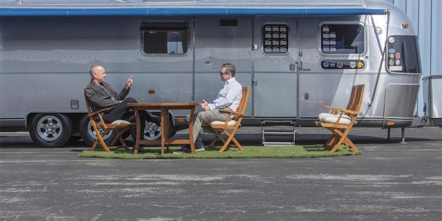 Tom Hanks talks to Bonhams Global Director of Motorsport Mark Osborne under the canopy of the 1992 Airstream travel trailer he's used on 18 filming sets.
