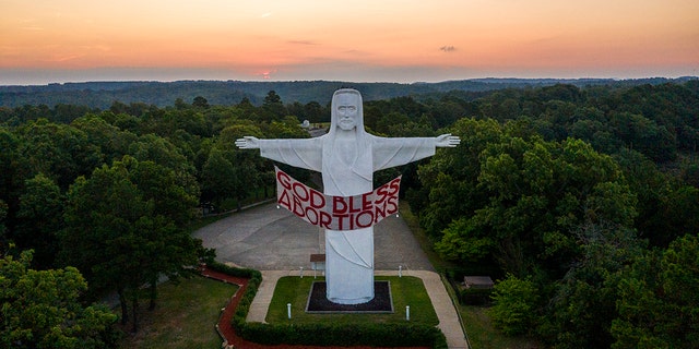 An activist art group called Indecline hung this banner at the Christ of the Ozarks statue in Eureka Springs, Arkansas on Thursday night.