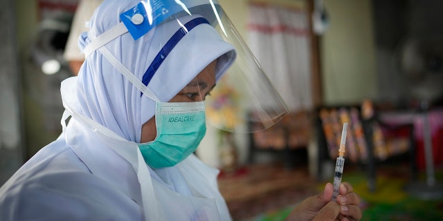 July 13, 2021: A nurse prepares to administer a Pfizer COVID-19 vaccine to an elderly woman in her house in rural Sabab Bernam, central Selangor state, Malaysia. 