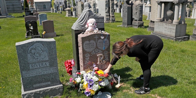 Sharon Rivera adjusts flowers and other items left at the grave of her daughter, 维多利亚州, at Calvary Cemetery in New York on Mother's Day. (AP Photo/Kathy Willens, 文件)