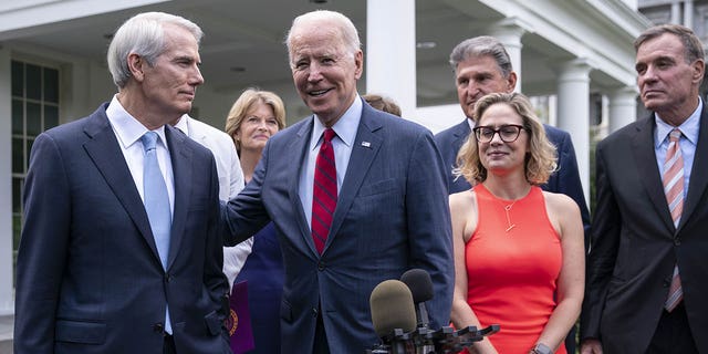 President Biden with the senators behind the bipartisan infrastructure bill. Negotiations were led by Sens. Rob Portman, R-Ohio, (left) and Kyrsten Sinema, D-Ariz., (middle right). 