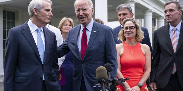 President Biden with the senators behind the bipartisan infrastructure bill. Negotiations were led by Sens. Rob Portman, R-Ohio, (left) and Kyrsten Sinema, D-Ariz., (middle right).