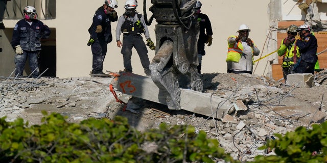Heavy machinery is used to remove a support column as search and rescue personnel work atop the rubble at the Champlain Towers South condo building on Friday. (AP)