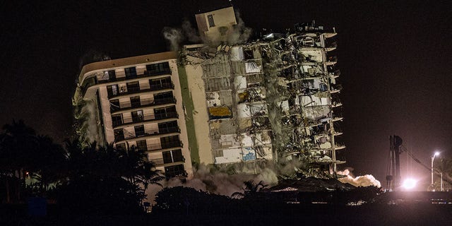 The rest of the Champlain South tower is seen being demolished in Surfside, Florida, north of Miami Beach, late on July 4, 2021. - A controlled explosion brought down the unstable remains of the collapsed apartment block in Florida late on July 4 ahead of a threatening tropical storm as rescuers prepare to resume searching for victims.