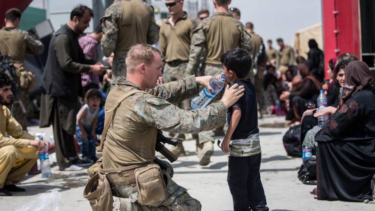 A Marine with the 24th Marine Expeditionary Unit (MEU) provides fresh water to a child during an evacuation at Hamid Karzai International Airport, Kabul, Afghanistan, Aug. 20. U.S. service members are assisting the Department of State with an orderly drawdown of designated personnel in Afghanistan. (U.S. Marine Corps photo by Sgt. Samuel Ruiz).