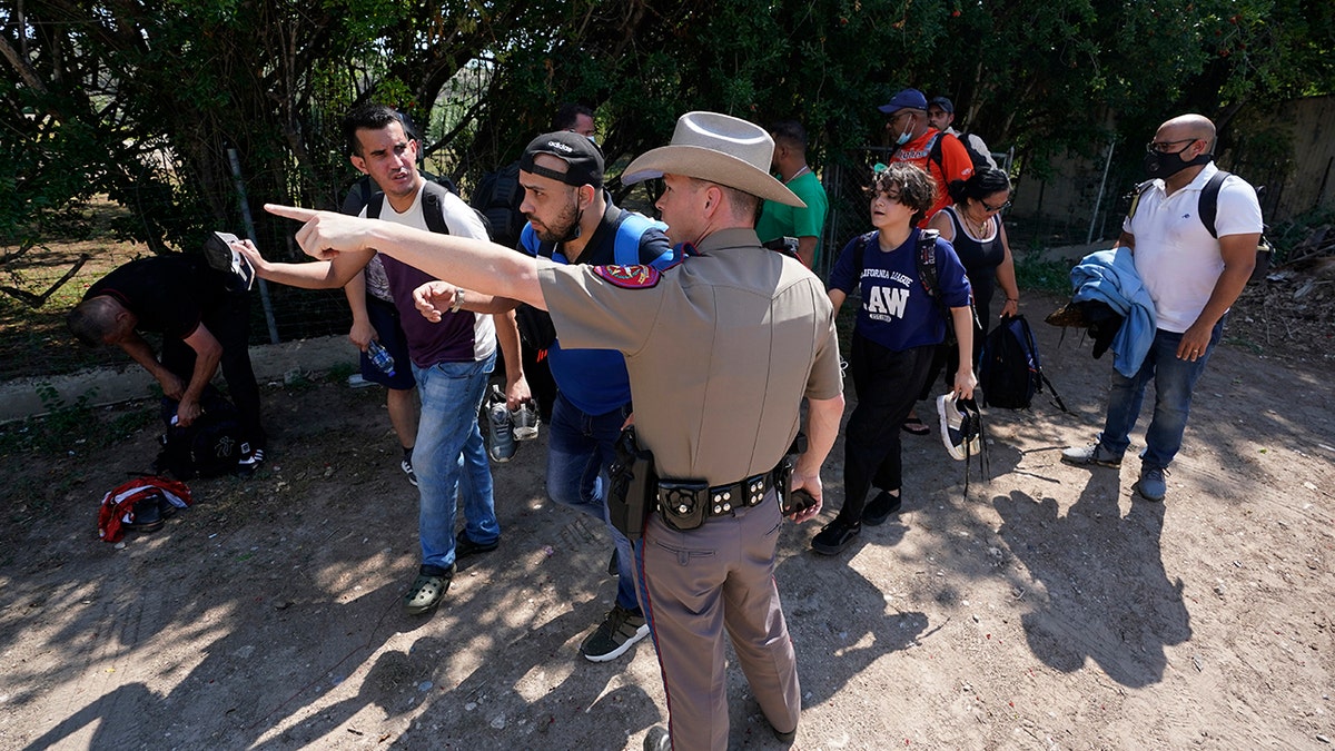 A Texas Department of Public Safety officer in Del Rio, Texas directs a group of migrants who crossed the border and turned themselves in on June 16, 2021. . (Associated Press)