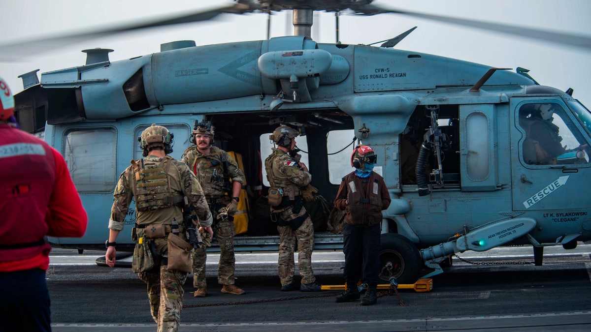 In this photo provided by the U.S. Navy, sailors assigned to an explosive ordnance unit board an MH-60S Seahawk helicopter on the flight deck of aircraft carrier USS Ronald Reagan to head to an oil tanker that was attacked off the coast of Oman in the Arabian Sea on Friday, July 30, 2021. 