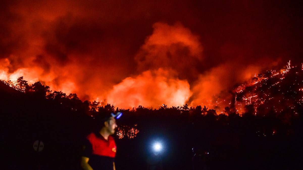 A man leaves as advancing fires rage the Hisaronu area, Turkey, Monday, Aug. 2, 2021. For the sixth straight day, Turkish firefighters battled Monday to control the blazes that are tearing through forests near Turkey's beach destinations.