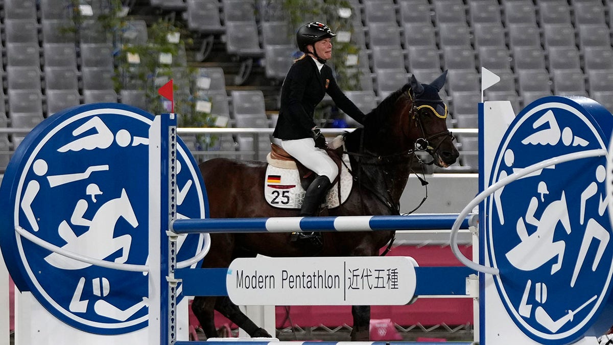 Annika Schleu of Germany cries as she couldn't controls her horse to compete in the equestrian portion of the women's modern pentathlon at the 2020 Summer Olympics, Friday, Aug. 6, 2021, in Tokyo, Japan.