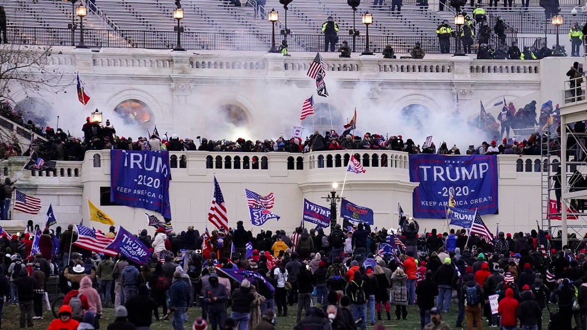 Jan. 6 Capitol Riot with protestors raising Trump flags and smoke brewing on the Capitol steps 