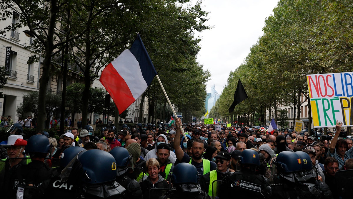 Anti-vax protesters face police during a protest against the vaccine and vaccine passports, in Paris, France, Saturday Aug. 7, 2021.