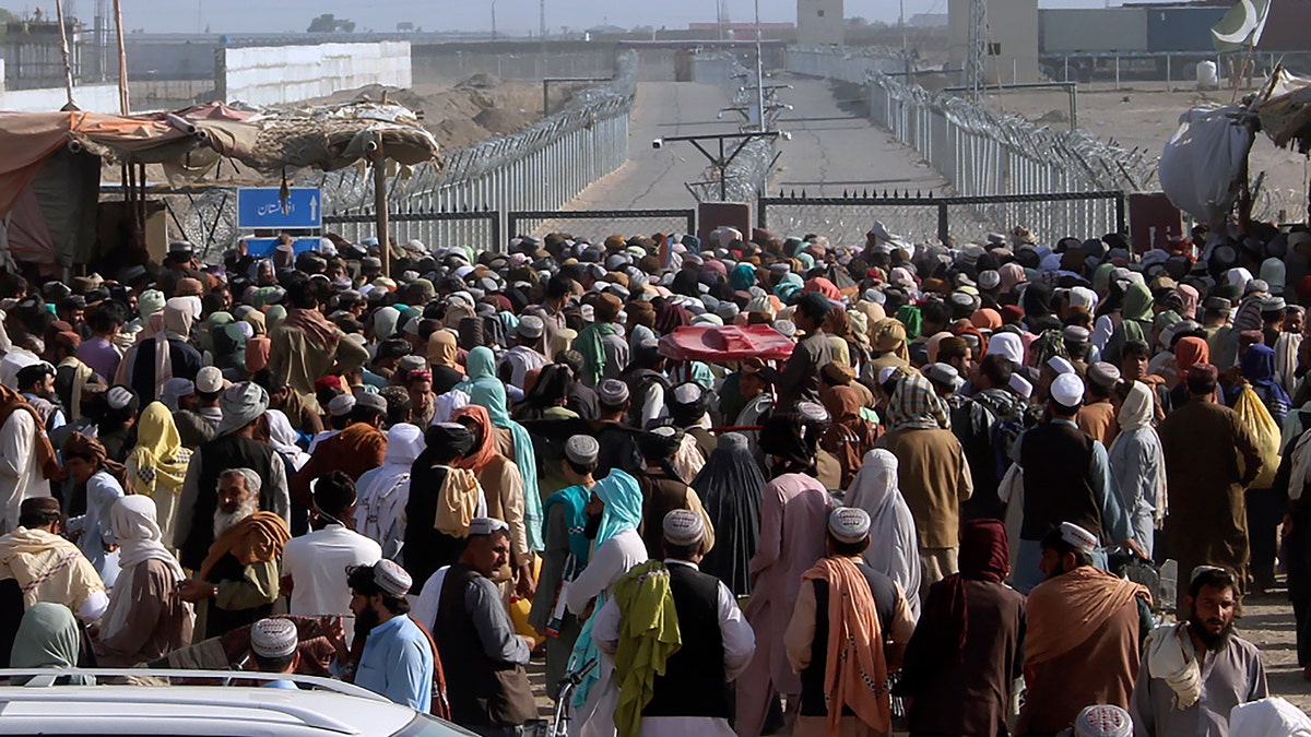 Stranded people gather to seek information from security forces about opening the border crossing between Pakistan and Afghanistan which was closed by authorities a few days ago in Chaman, Pakistan, Wednesday, Aug. 11, 2021. Normally thousands of Afghans and Pakistanis cross daily and a steady stream of trucks passes through, taking goods to landlocked Afghanistan from the Arabian Sea port city of Karachi in Pakistan. (AP Photo/Jafar Khan)