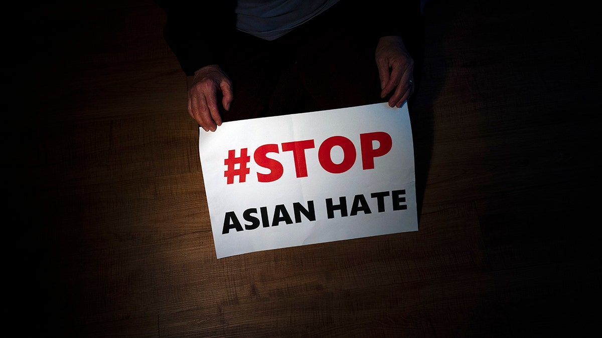 FILE - In this March 31, 2021, file photo, Jen Ho Lee, a 76-year-old South Korean immigrant, poses in her apartment in Los Angeles with a sign from a recent rally against anti-Asian hate crimes she attended.
