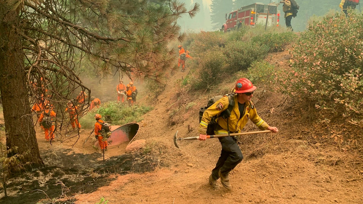 CalFire firefighters and California Correctional Center (CCC) inmates fight a spot fire on the side of Highway CA-36 between Chester and Westwood in Plumas County, Calif., Friday, Aug. 13, 2021. In California, the Dixie Fire that virtually destroyed the Sierra Nevada town of Greenville is less than a third surrounded. Fire officials say Northern California will have dangerous fire weather on Friday, including possible lightning that could spark more blazes. Climate change has made the U.S. West warmer and drier in the past 30 years and will continue to make the weather more extreme and wildfires more destructive, according to scientists. (AP Photo/Eugene Garcia)