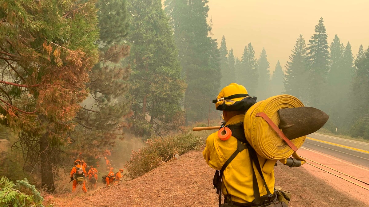 CalFire firefighters and California Correctional Center (CCC) inmates fight a spot fire on the side of Highway CA-36 between Chester and Westwood in Plumas County, Calif., Friday, Aug. 13, 2021. In California, the Dixie Fire that virtually destroyed the Sierra Nevada town of Greenville is less than a third surrounded. Fire officials say Northern California will have dangerous fire weather on Friday, including possible lightning that could spark more blazes.(AP Photo/Eugene Garcia)