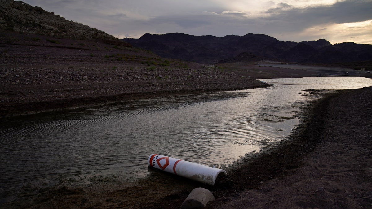A buoy once used to warn of a submerged rock rests on the ground along the waterline near a closed boat ramp on Lake Mead at the Lake Mead National Recreation Area, Friday, Aug. 13, 2021, near Boulder City, Nev. Water levels at Lake Mead, the largest reservoir on the Colorado River, have fallen to record lows. (AP Photo/John Locher)
