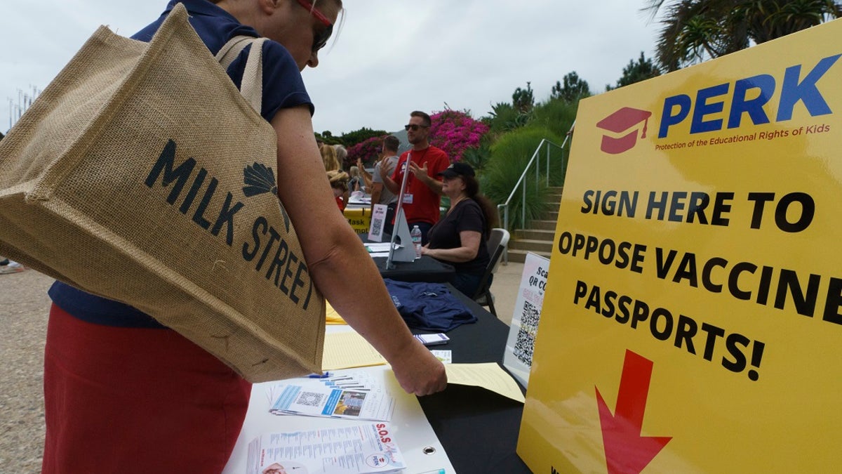 People sign forms to oppose vaccine passports as they participate at the "S.O.S California No Vaccine Passport Rally" at Tongva Park in Santa Monica, Calif., on Saturday. A vaccine worker was struck by a motorist in San Clarita that may have been intentional, authorities said. (AP Photo/Damian Dovarganes)