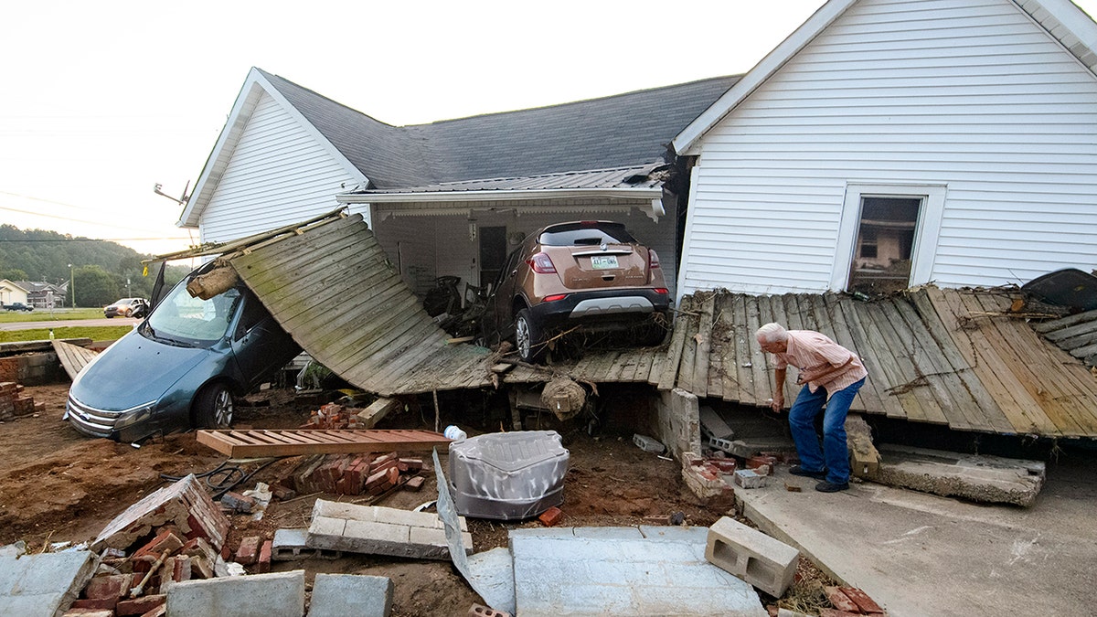Ernest Hollis looks for items at his granddaughter's house that was devastated by floodwaters, Monday, Aug. 23, 2021, in Waverly, Tenn. Heavy rains caused flooding in Middle Tennessee days ago and have resulted in multiple deaths, and missing people as homes and rural roads were also washed away. (AP Photo/John Amis)