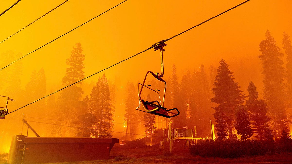 Seen in a long camera exposure, the Caldor Fire burns as a chair lift sits at the Sierra-at-Tahoe ski resort on Sunday, Aug. 29, 2021, in Eldorado National Forest, Calif. The main buildings at the ski slope's base survived as the main fire front passed. (AP Photo/Noah Berger)