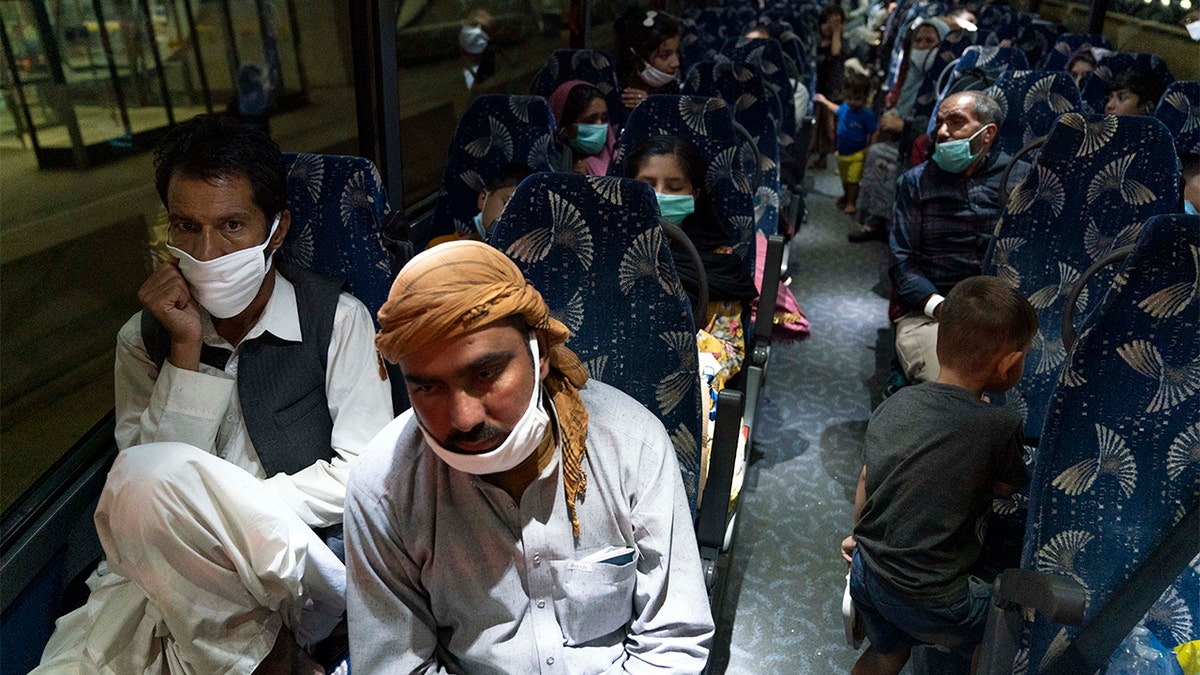 Families evacuated from Kabul, Afghanistan, sit on a bus after they arrived at Washington Dulles International Airport in Chantilly, Va., Saturday, Aug. 21, 2021.