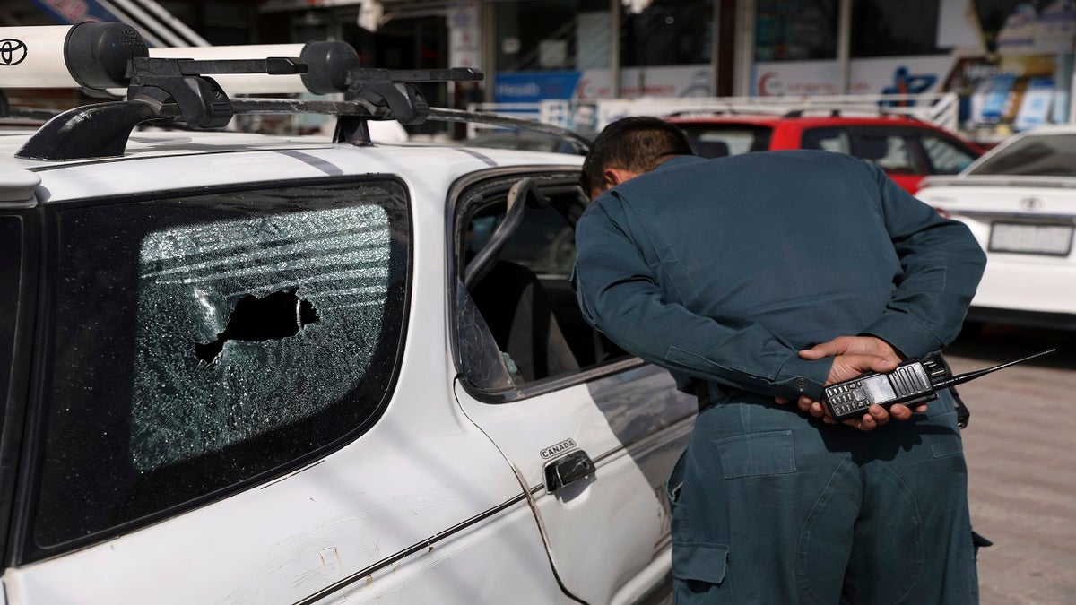 An Afghan police officer inspects the car after director of Afghanistan's Government Information Media Center Dawa Khan Menapal was shot dead in Kabul, Afghanistan, on Friday.?