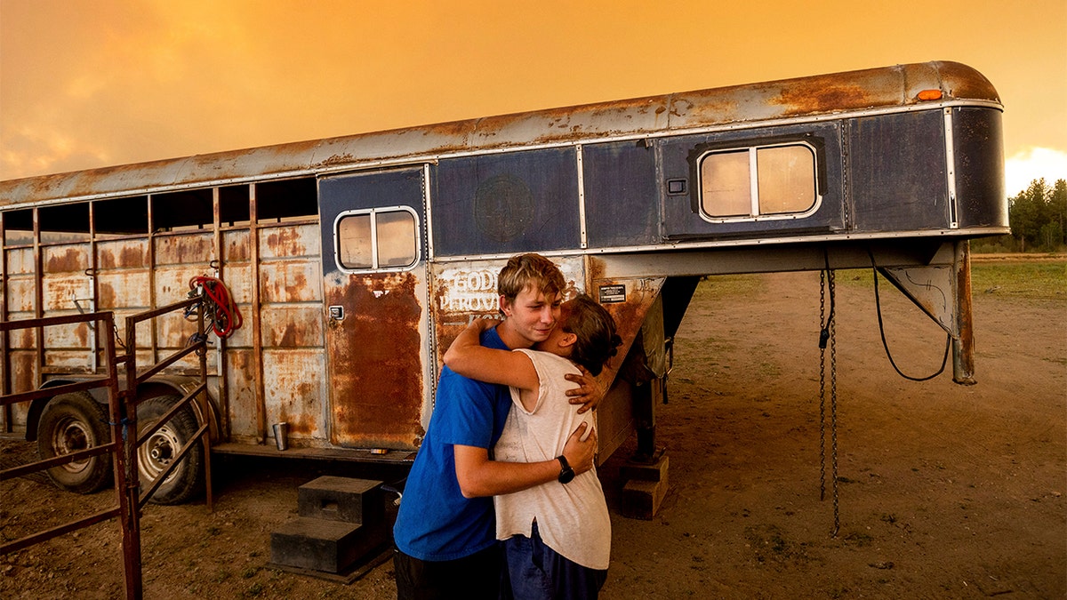 Hunter McKee hugs Dawn Garofalo after helping her evacuate her horses to the edge of Lake Almanor as the Dixie Fire approaches Chester, Calif, on Tuesday, Aug. 3, 2021. Officials issued evacuation orders for the town earlier in the day as dry and windy conditions led to increased fire activity. 
