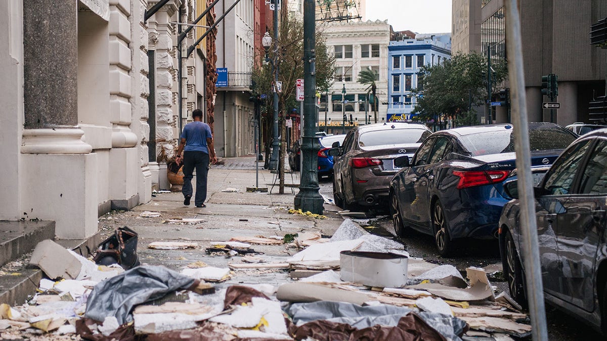 A person walks past debris on the sidewalk after Hurricane Ida passed through on Aug. 30, 2021 in New Orleans, Louisiana. Ida made landfall as a Category 4 hurricane yesterday in Louisiana and brought flooding and wind damage along the Gulf Coast.