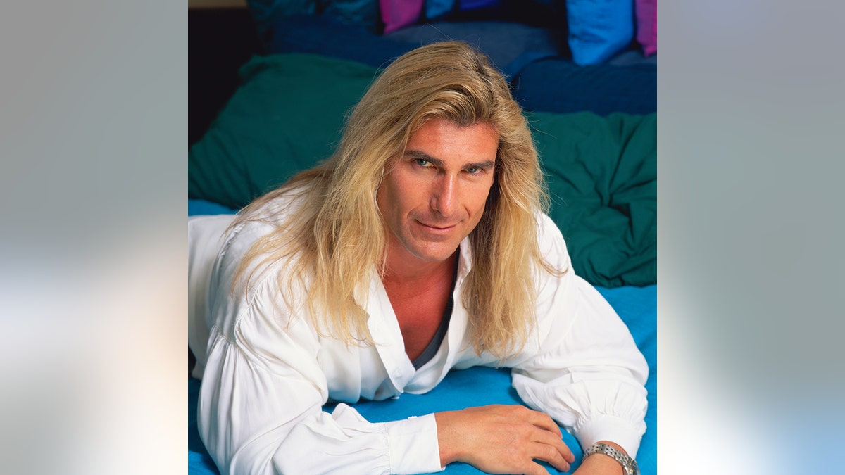 Fabio models a white blouse with his long blonde hair.