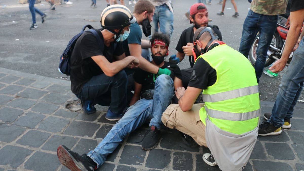 Protesters tend to a man injured during demonstrations on the anniversary of a massive explosion in Beirut.