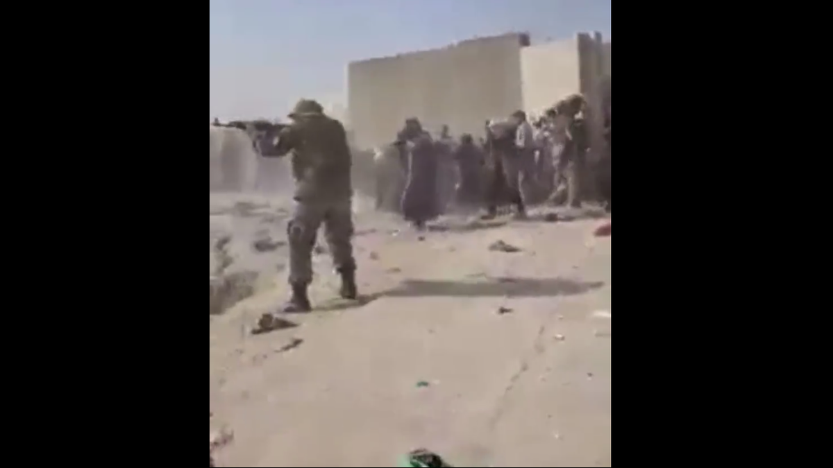 People take cover near Kabul's airport as guns are fired Thursday.