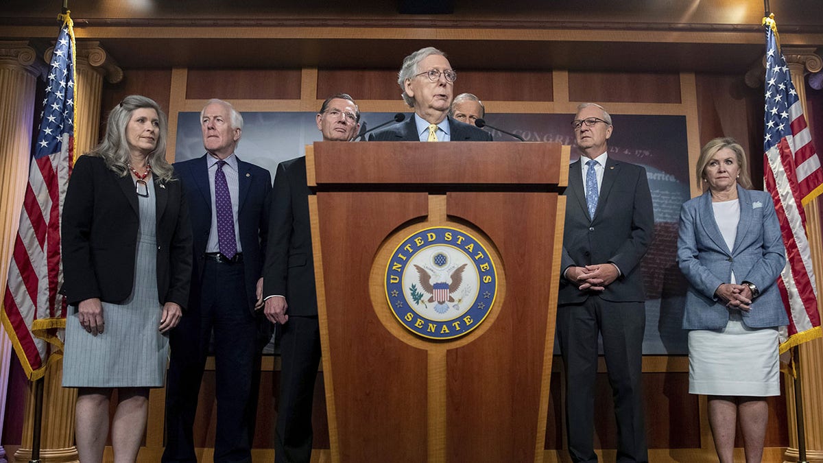 Sen. Mitch McConnell stands with other Republican senators during a press conference.