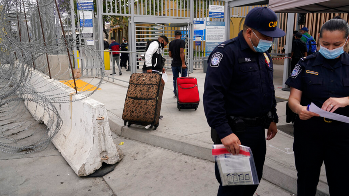 FILE: Honduran Alex Cortillo, left, and his stepbrother pull their suitcases to the border crossing into the U.S. to begin the asylum process, in Tijuana, Mexico. 
