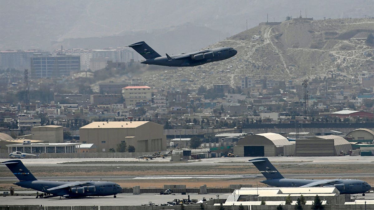 A plane takes off from the Kabul airport with a city landscape in the background