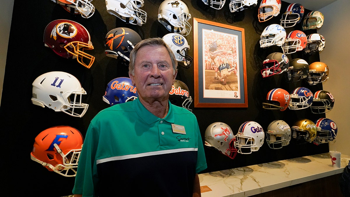 Steve Spurrier standing in front of a display of football helmets at the Gridiron Grill in Gainesville, Fla.