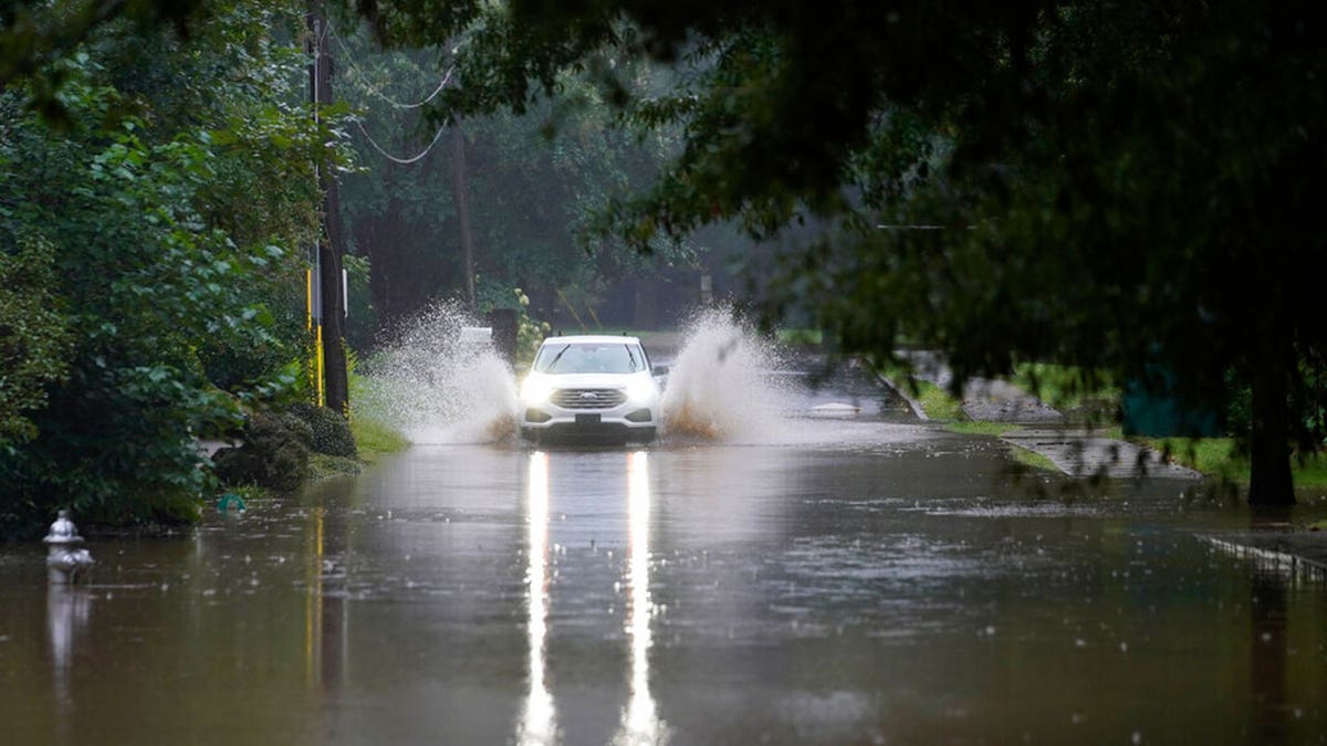 A car attempts to drive through flood waters near Peachtree Creek near Atlanta, as Tropical Storm Fred makes its way through north and central Georgia on Tuesday, Aug. 17, 2021. 